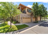 Beautiful townhome featuring a stone facade, attached garages, and an upper balcony overlooking the well-maintained street at 10064 Bluffmont Ct, Lone Tree, CO 80124