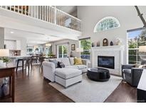 Open-concept living room with hardwood floors, a fireplace, and large windows letting in natural light at 4976 S Nelson St # A, Littleton, CO 80127