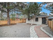 Charming home features a well-maintained front yard with beautiful landscaping, a quaint stone path, and privacy fencing at 1362 Wolff St, Denver, CO 80204
