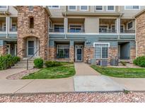 Inviting condo exterior featuring stone accents, a well-maintained lawn, and a sidewalk to the front door at 457 Black Feather Loop # 702, Castle Rock, CO 80104