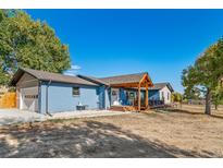 Charming blue home featuring a well-maintained front yard, inviting porch, and an attached garage at 6365 W Coal Mine Ave, Littleton, CO 80123