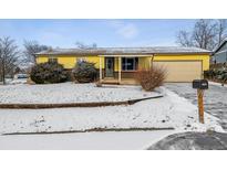 Charming single-story home with a yellow exterior and attached garage, surrounded by a snowy front yard landscape at 3052 S Joplin Ct, Aurora, CO 80013