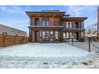 Modern two-story home featuring brick facade, balconies, and large windows, set against a snowy front yard at 1864 W 41St Ave, Denver, CO 80211