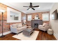 Cozy living room with brick accent wall, fireplace, and neutral-toned furniture; ceiling fan above at 3176 Depew St, Wheat Ridge, CO 80214