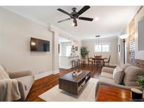 Open living room with hardwood floors, ceiling fan, and breakfast bar overlooking the kitchen at 3176 Depew St, Wheat Ridge, CO 80214