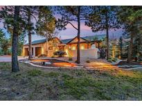 Stunning home exterior with stucco walls, mature trees, and warm lighting creating a welcoming ambiance at 17995 Minglewood Trl, Monument, CO 80132