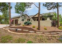Stunning stucco home with a charming, landscaped front yard and mature pine trees at 17995 Minglewood Trl, Monument, CO 80132