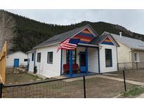 Charming white home with colorful accents, an American flag, and a cozy front porch at 215 Colorado Blvd, Idaho Springs, CO 80452