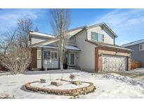 Charming two-story home with a brick facade and well-manicured front yard covered in winter snow at 14558 Vine St, Thornton, CO 80602