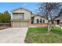Charming two-story home featuring a well-maintained lawn, brick accents, and an attached two-car garage at 8174 Field Cir, Arvada, CO 80005