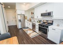Stylish kitchen with stainless steel appliances, subway tile backsplash, and sleek white cabinetry at 2876 W 53Rd Ave # 106, Denver, CO 80221