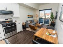 Modern living room featuring a gray sofa, wood floors, and a sliding glass door to a balcony at 2876 W 53Rd Ave # 106, Denver, CO 80221
