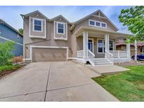 Charming two-story home featuring a covered porch, two-car garage, and manicured lawn at 8545 Braun Loop, Arvada, CO 80005