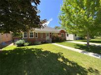 Charming single-story red brick house featuring a well-manicured lawn and mature trees in a residential neighborhood at 1273 S Jackson St, Denver, CO 80210