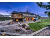 Inviting home exterior with a large glass sunroom, stone patio, fire pit, and well-manicured lawn at 18045 Sunburst Dr, Monument, CO 80132