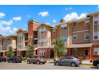 A multi-story condo building showcasing a beige facade, brick accents, and well-maintained landscaping at 8467 Canyon Rim Cir # 302, Englewood, CO 80112