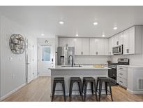 Modern kitchen features sleek white cabinets, stainless steel appliances, and breakfast bar with stylish stools at 1143 Hummingbird Cir, Longmont, CO 80501