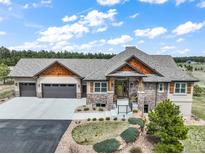 Charming home featuring a stone facade, cedar accents, a three-car garage, and professionally landscaped front yard at 17275 Gwilym Ct, Monument, CO 80132