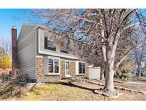 Charming two-story home with brick and siding, complemented by a lush green lawn and mature trees at 1050 S Lewiston Way, Aurora, CO 80017