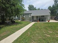 Charming stone home featuring a well-manicured lawn, sidewalk and covered front porch with stylish outdoor decor at 1930 Alton St, Aurora, CO 80010