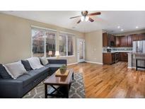Open living room featuring hardwood floors, large windows, and a gray sectional sofa at 10247 Telluride Way, Commerce City, CO 80022