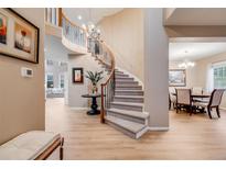 Spacious entryway featuring a curved staircase with iron railings and views into the dining and living areas at 7329 Arco Iris Ln, Castle Pines, CO 80108