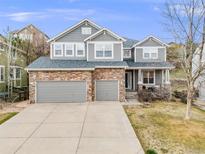 Charming two-story home with a stone facade, three-car garage and beautifully landscaped front yard at 7329 Arco Iris Ln, Castle Pines, CO 80108