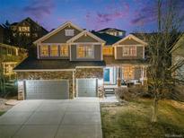 Charming two-story home featuring a stone facade, three-car garage, and inviting front porch with a blue door at 7329 Arco Iris Ln, Castle Pines, CO 80108