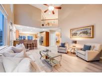 Bright living room open to the kitchen with light wood floors, neutral colors, and a soaring ceiling at 7329 Arco Iris Ln, Castle Pines, CO 80108