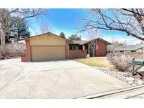 Charming single-story brick home featuring a spacious driveway and mature landscaping on a sunny day at 7019 S Windermere St, Littleton, CO 80120