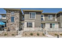 A modern townhome featuring a stone facade and a cozy front porch with light-colored railing at 16433 Askins Loop, Parker, CO 80134