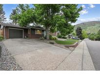Charming brick home with mature landscaping and a large driveway on a sunny day at 632 Wyoming St, Golden, CO 80403