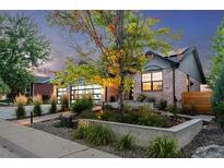 Charming brick home boasts a modern garage door and beautifully landscaped front yard at dusk at 9161 W Lake Dr, Littleton, CO 80123