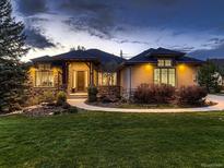 Stunning single-story home with stone accents, well-lit windows, and lush lawn at dusk at 5441 Twilight Way, Parker, CO 80134