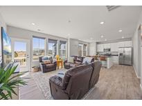 Open-concept living room and kitchen with hardwood floors, stainless steel appliances, and lots of natural light at 1917 S Fultondale Way, Aurora, CO 80018