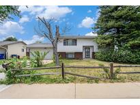 Charming home with a yard featuring a rustic fence and mature trees under a bright sky at 757 Norfolk Way, Aurora, CO 80011