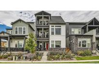 Beautiful three-story townhome featuring a red front door, stone accents, and dual upper level balconies at 16546 Umatilla Place, Broomfield, CO 80023