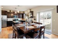 Inviting dining area featuring a dark wood table with seating for eight, adjoining a modern kitchen with stainless steel appliances at 5563 S Elk Ct, Aurora, CO 80016