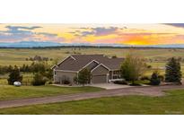 Charming single-Gathering home features a well-manicured lawn and a gravel driveway leading up to a 2-car garage at 6785 Arrowhead Cir, Elizabeth, CO 80107