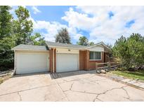 Charming brick home featuring an attached two car garage and a cracked concrete driveway at 12154 E Virginia Dr, Aurora, CO 80012