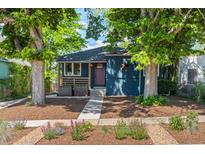 Charming blue home with a landscaped front yard, healthy mature trees, and a welcoming red door at 2577 Depew St, Edgewater, CO 80214