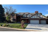 Charming brick two-story home with a tile roof, manicured lawn, and three-car garage at 6414 E Stanford Ave, Cherry Hills Village, CO 80111