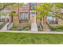 Beautiful brick townhome featuring a meticulously maintained landscaped front yard and welcoming entry stairs at 10311 Belvedere Ln, Lone Tree, CO 80124