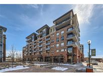 Modern condo building featuring brick facade, glass balconies, and sleek architectural design against a clear blue sky at 20 Wilcox St # 518, Castle Rock, CO 80104