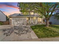 Charming two-story home with stone accents, lush green lawn, and mature tree at 524 Rider Ridge Dr, Longmont, CO 80504