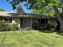 Charming brick home with a well-manicured lawn and mature trees providing shade at 1602 S Lamar St, Lakewood, CO 80232