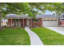 Brick ranch home with landscaped lawn, walkway, and attached garage at 476 S Newport Way, Denver, CO 80224