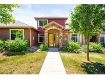 Inviting two-story home features a stone entrance, colorful facade, and well-maintained landscaping at 8571 Gold Peak Dr # F, Highlands Ranch, CO 80130