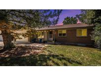 Charming brick home featuring a well-manicured lawn, mature tree, and inviting front porch with chairs at 16917 E Eldorado Cir, Aurora, CO 80013
