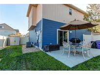 Cozy backyard patio with seating, umbrella, and well-maintained lawn, perfect for outdoor entertaining at 19149 E 55Th Ave, Denver, CO 80249